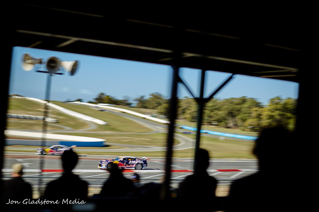 Silhouettes of people with race cars going past in the background